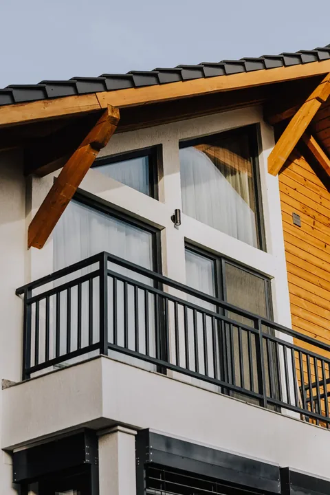 Balconul de la etaj, cu ferestre antracit sub streașina din lemn