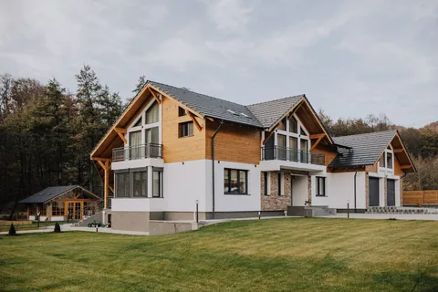 Casa văzută din grădină, cu frontoanele din lemn și fațada albă